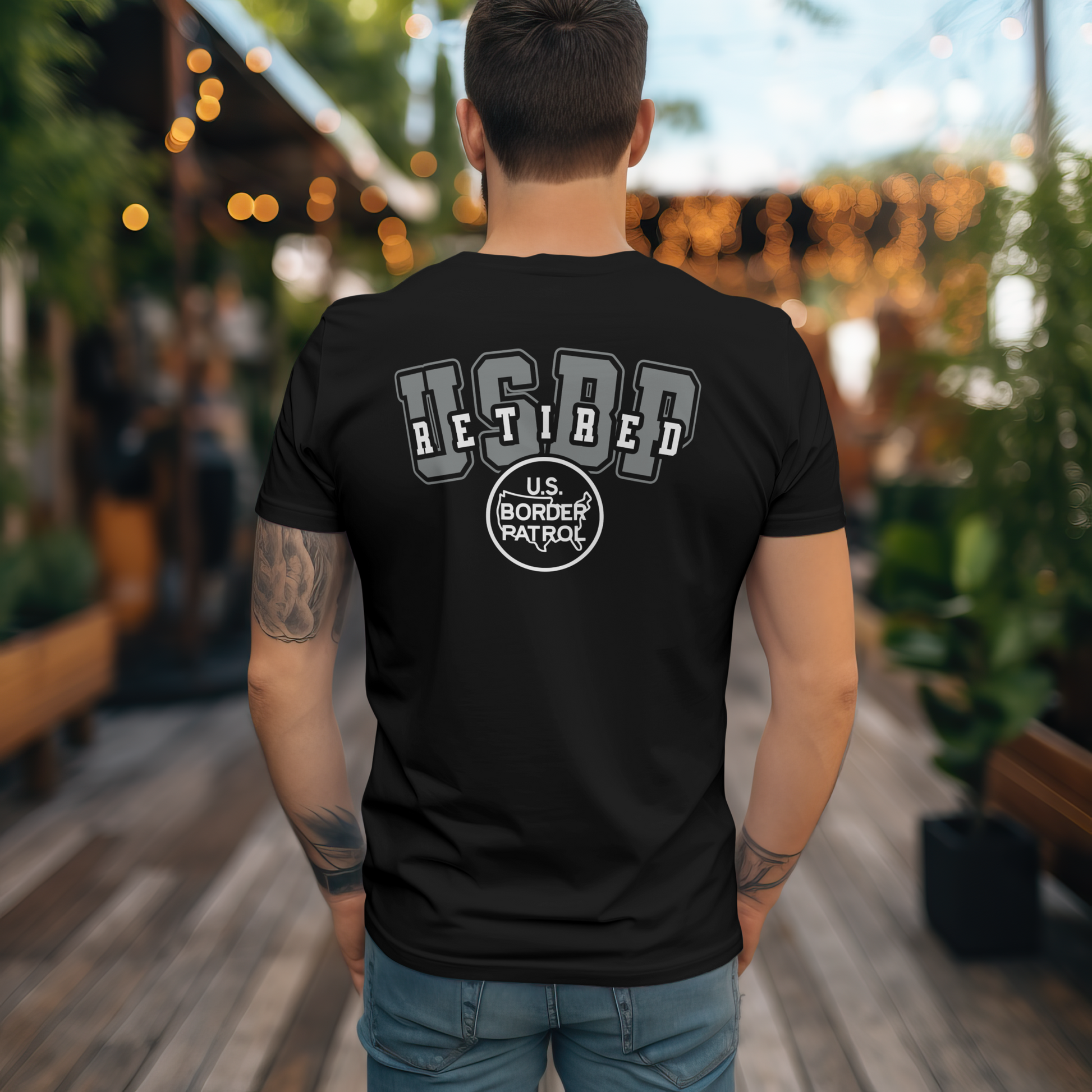 Person wearing a black t-shirt with 'Retired U.S. Border Patrol' text outdoors.