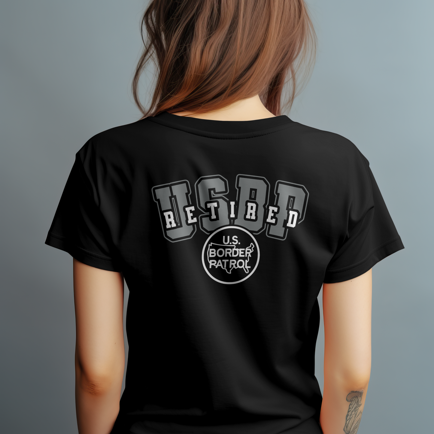 Black t-shirt with 'US Border Patrol Retired' text on the back, worn by a person against a gray background.